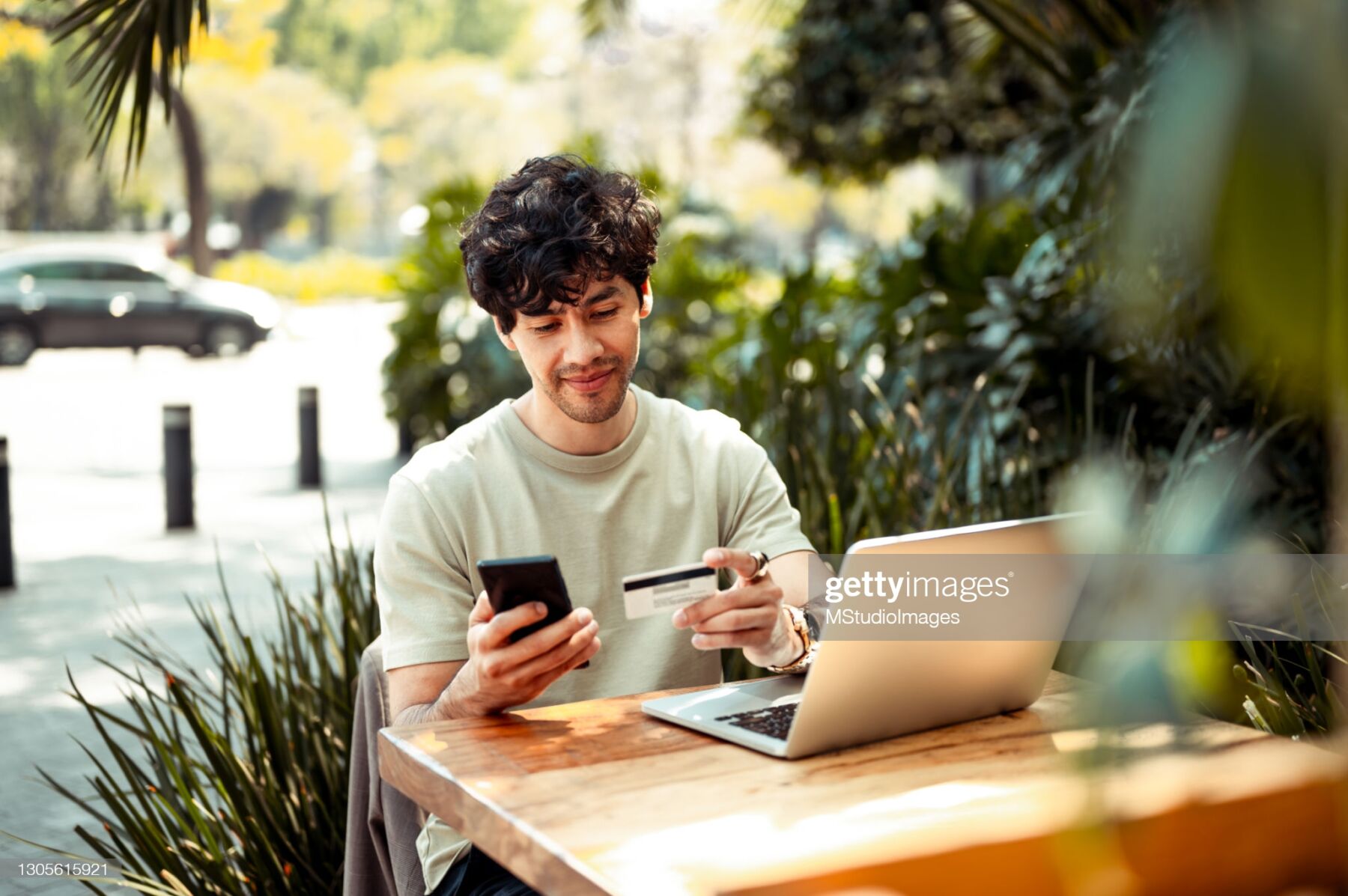 Young man sitting at the cafe and paying online with credit card