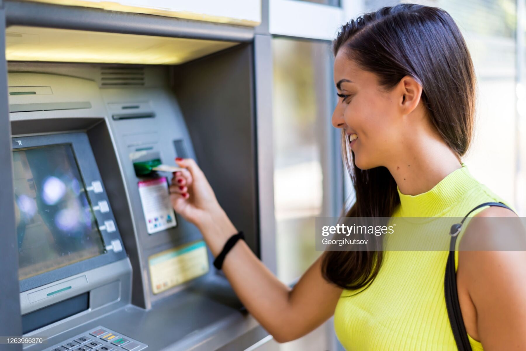 Smiling woman at the ATM ready to withdraw cash money